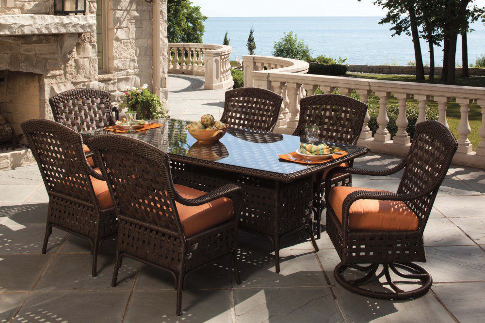 A view of an outdoor, wicker dining set by the sea.