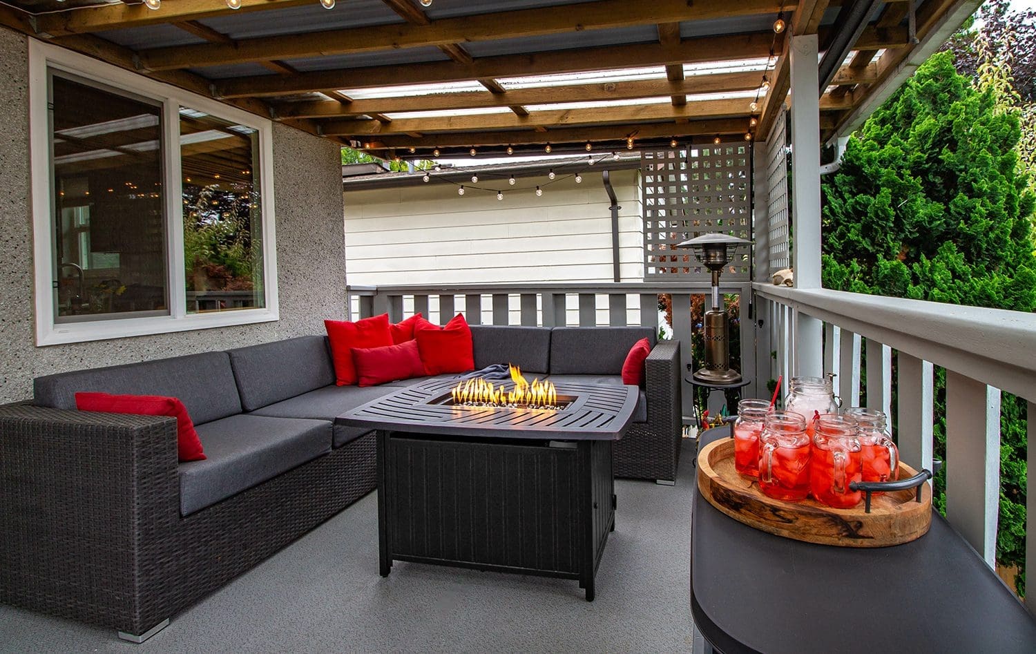 an outdoor sectional with charcoal gray cushions and red accent pillows